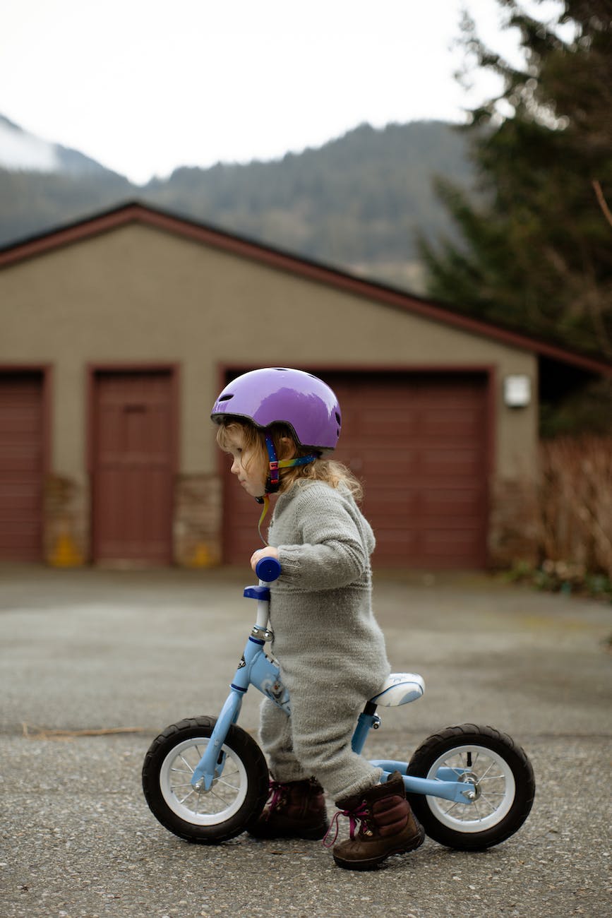 cute child riding balance bike on street in countryside