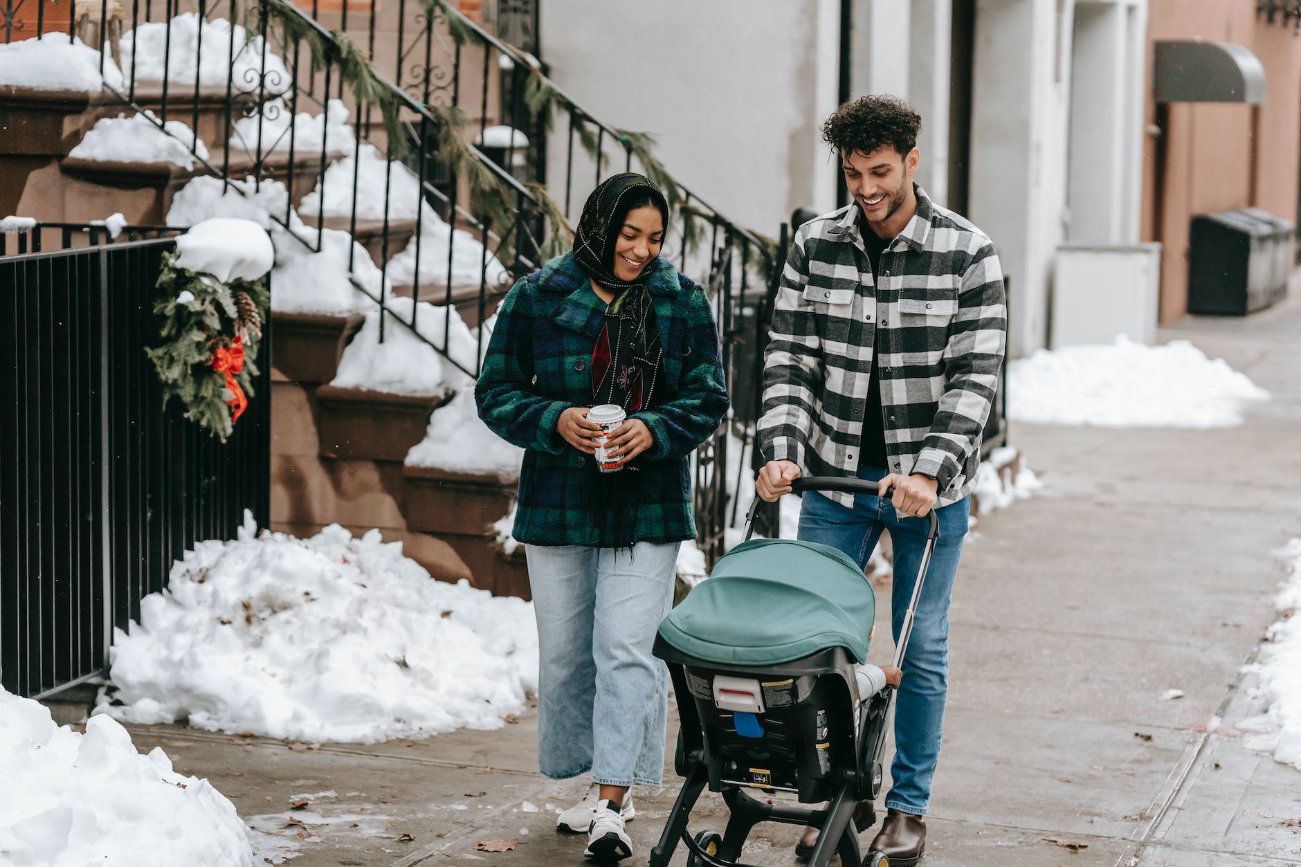 positive ethnic couple having stroll with baby in stroller